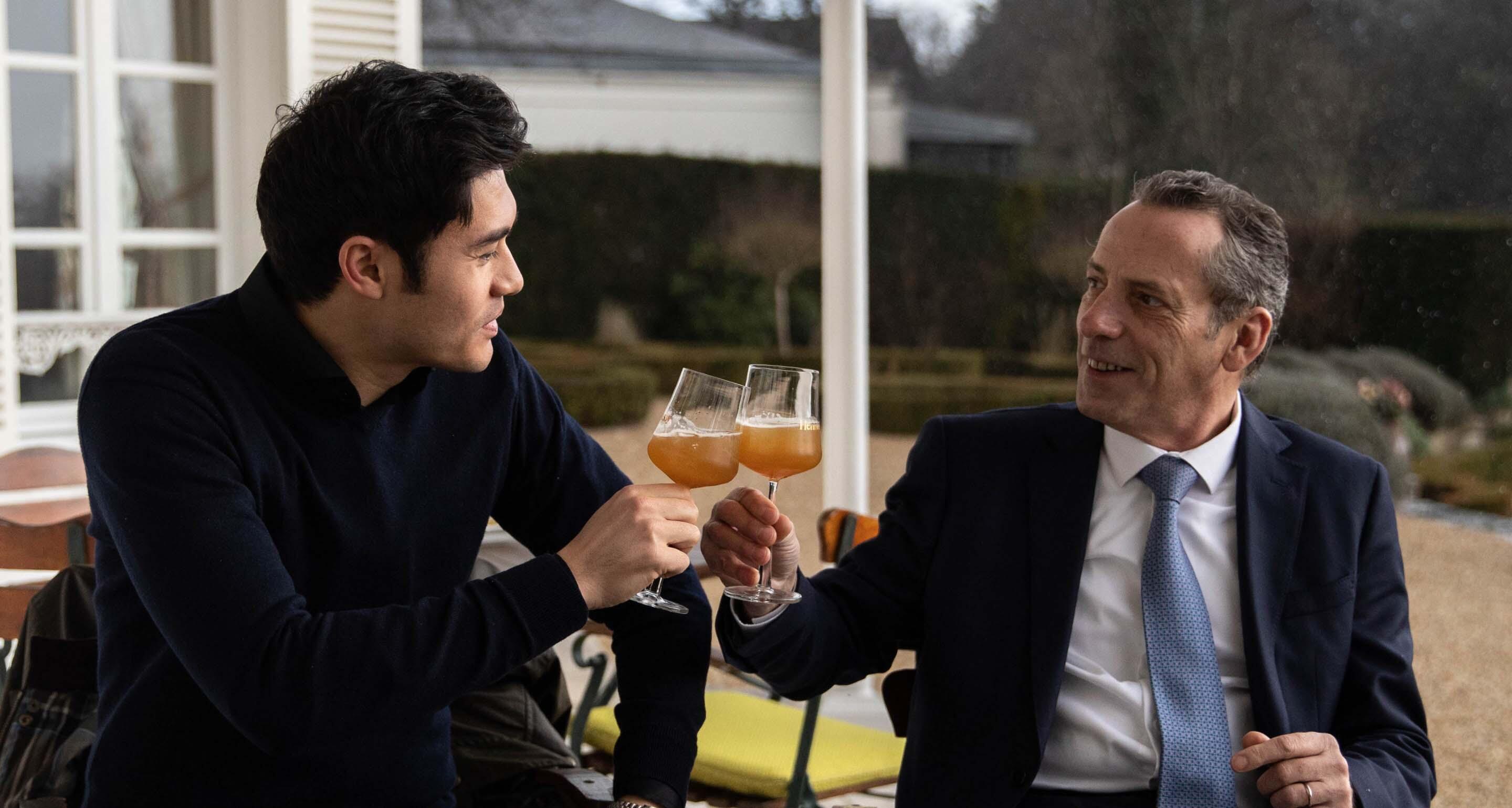 Henry Golding toasts Olivier Paultes, Hennessy’s Director of Distilleries and member of the Tasting Committee, with a Hennessy X.O cocktail on the grounds of the Hennessy Maison in Cognac.