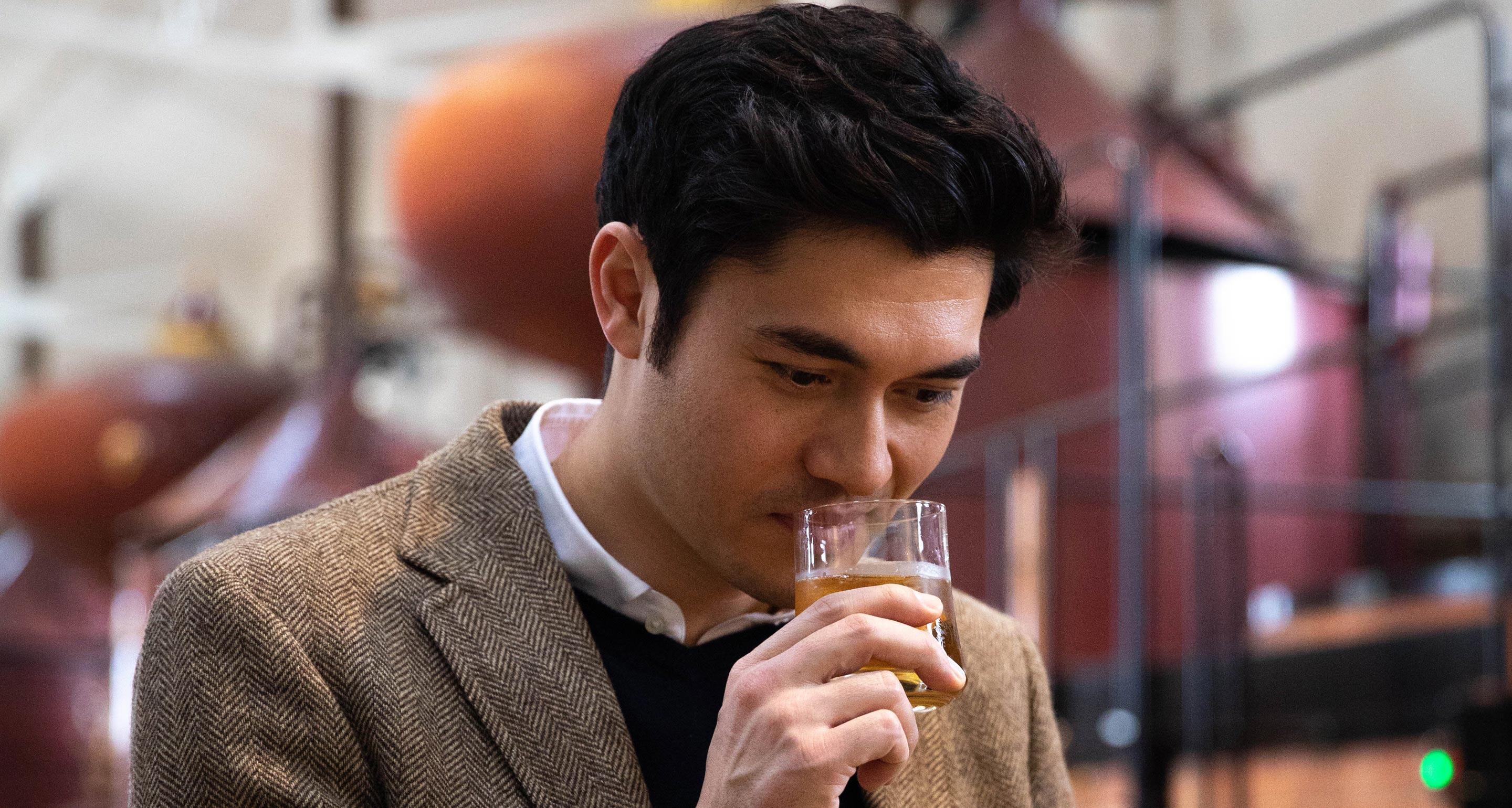 Henry Golding samples eau-de-vie in the Hennessy cognac distillery.