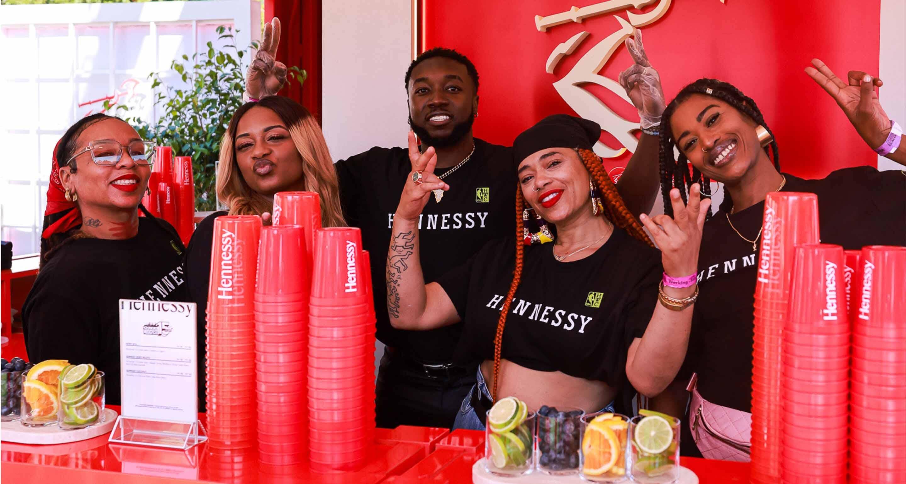 Hennessy team smiling and ready to serve drinks at the lively festival cocktail experience zone.