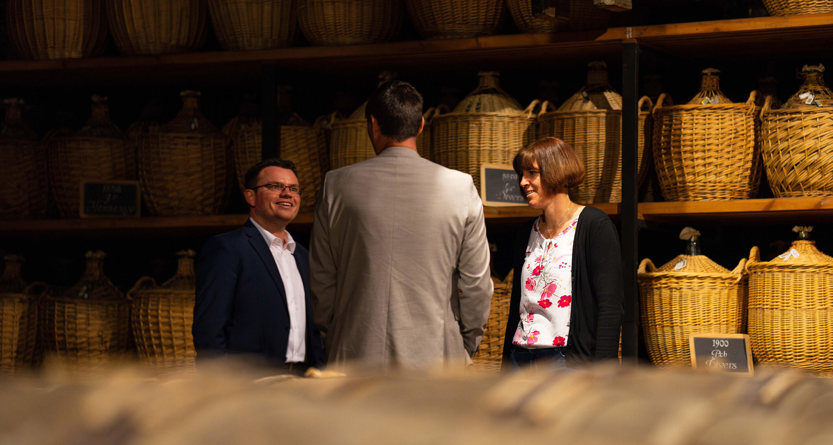 Guided tour in one of Hennessy's historical cellars, with rows of glass demi-johns countaining old eaux-de-vie in the background