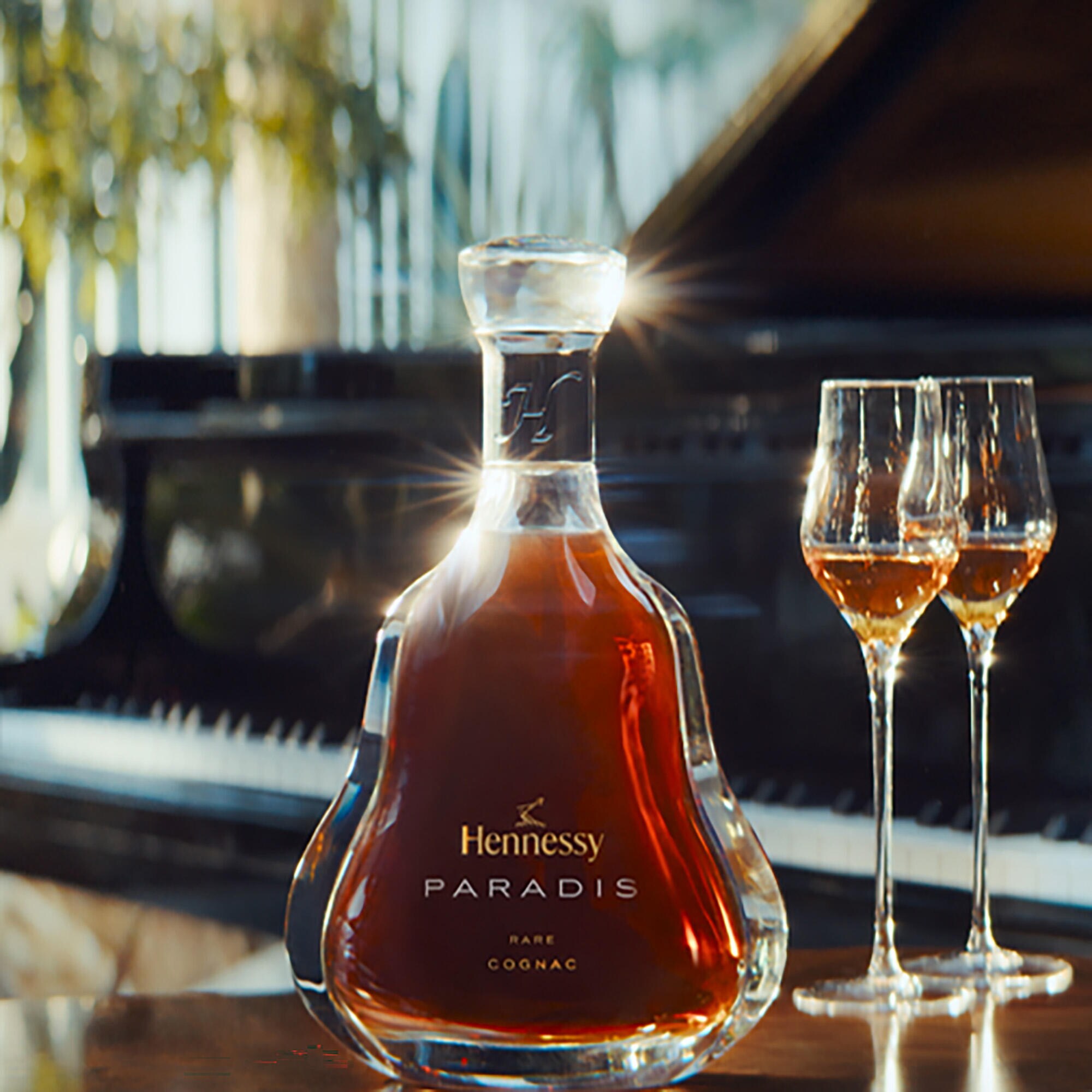 Decanter of Hennessy Paradis with 2 crystal glasses, in front of a grand piano