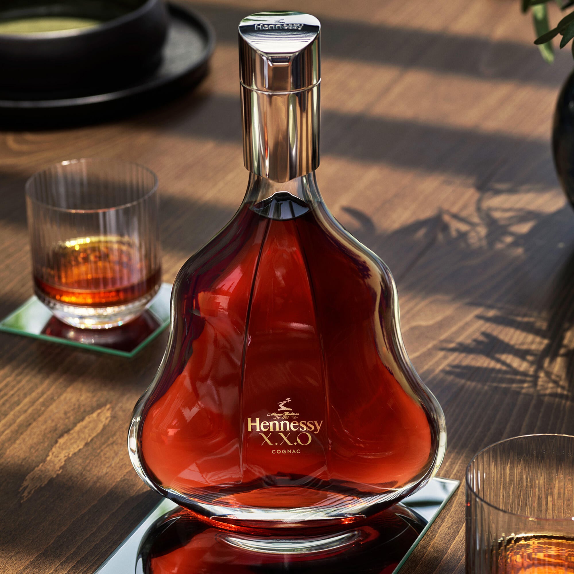 Decanter of Hennessy X.X.O on a table, with a glass of cognac served neat